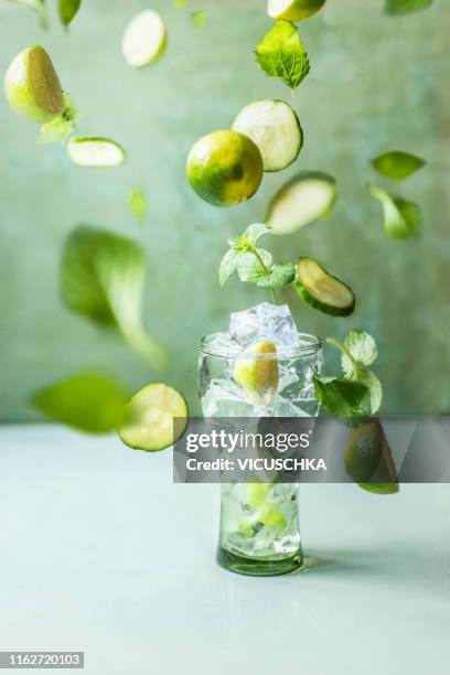 iced summer drink in glass with flying green ingredients - infused water stockfoto's en -beelden