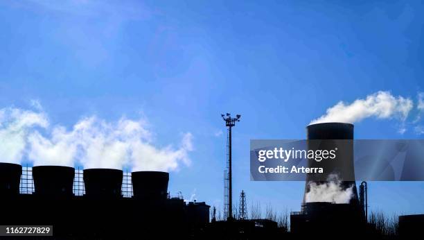 Industrial estate showing cooling tower and chimneys silhouetted against blue sky at the BASF chemical production site in the port of Antwerp,...