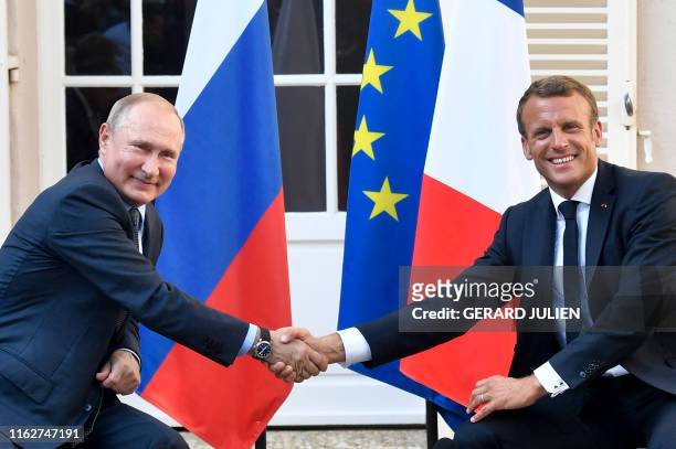 French President Emmanuel Macron shakes hands with Russia's President Vladimir Putin at the end of their meeting, at his summer retreat of the...