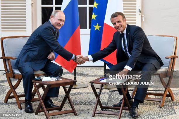 French President Emmanuel Macron shakes hands with Russia's President Vladimir Putin at the end of their meeting, at his summer retreat of the...