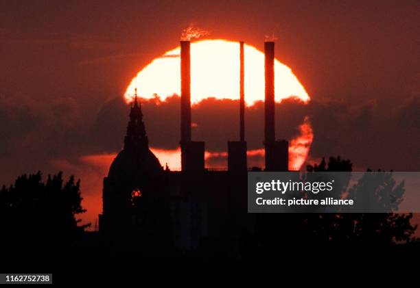 August 2019, Lower Saxony, Hanover: The sun sets behind the New Town Hall and the Linden combined heat and power station . Photo: Julian...