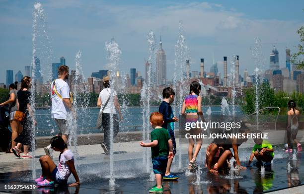 Children cool themself in a fountain in the Domino Park next to the East River on August 19, 2019 in New York City.