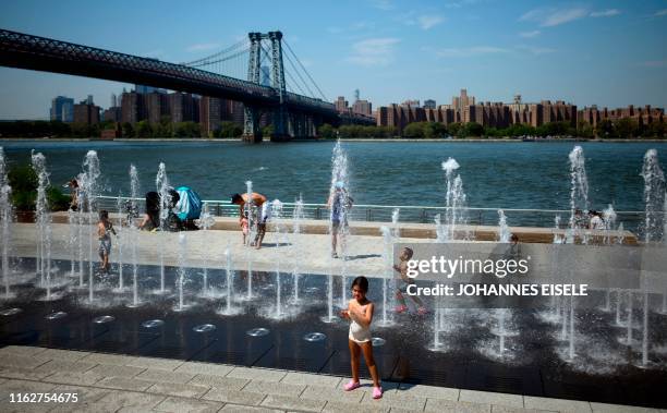 Children cool themself in a fountain in the Domino Park next to the East River on August 19, 2019 in New York City.