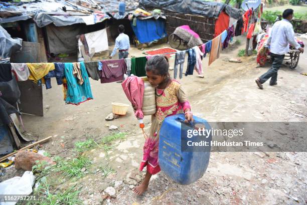 Child carries her belongings while shifting to a portable tent installed by the Department of Irrigation and Flood Control of Delhi for people living...