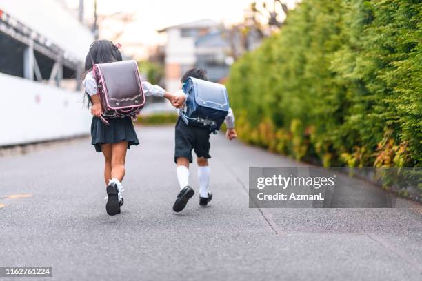 japanese schoolchildren holding hands and running - boy running back stock pictures, royalty-free photos & images