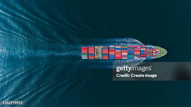 aerial top view container ship at seaport or container warehouse and working crane bridge loading container for logistics, import export, shipping or transportation. - containerschip stockfoto's en -beelden