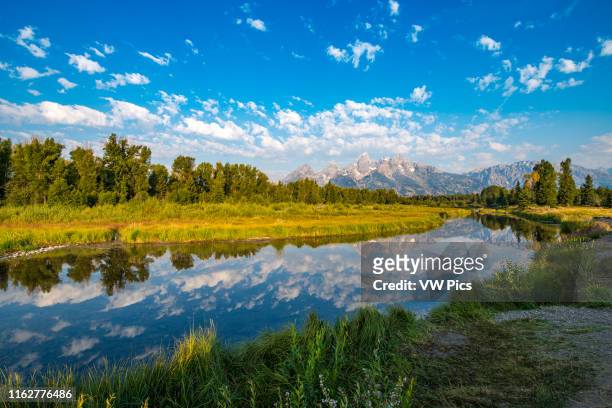 Still waters of the Snake River reflects Teton Mountain Race and cloudy skies, Grand Tetons National Park, Teton County, Wyoming