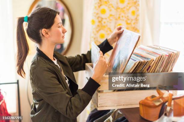young woman looking at records in a thrift store - coleção imagens e fotografias de stock