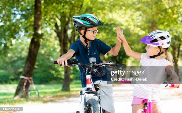 kinderen fietsen hoog-vijf - family with two children stockfoto's en -beelden