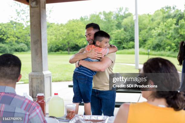 onkel umarmt jungen neffen vor dem mittagessen im park. - onkel stock-fotos und bilder