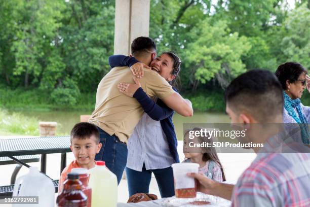 abraço dos primos na reunião do piquenique prendida no parque - casa de jardim ou parque - fotografias e filmes do acervo