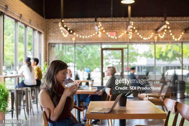 zakenvrouw beoordelingen document op laptop - café stockfoto's en -beelden