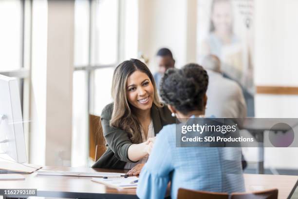 when the loan is processed, bank manager shakes customer's hand - bankers imagens e fotografias de stock