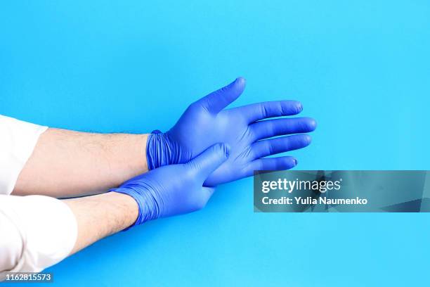 medicine and surgery theme: doctor putting on protective blue gloves. - washing up glove - fotografias e filmes do acervo