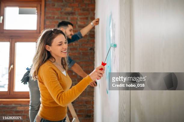 pareja pintando paredes de casa juntas - reforma assunto fotografías e imágenes de stock