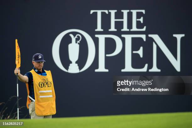 John Wood, caddie for Matt Kuchar of the United States holds the flag on the 18th green during the first round of the 148th Open Championship held on...