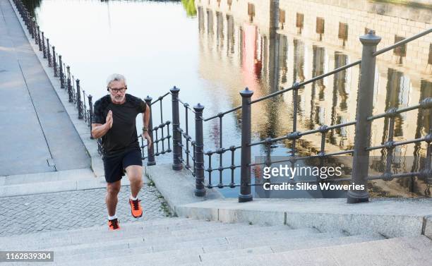portrait of an active senior man doing exercise in the city of berlin - jogging stock-fotos und bilder