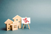 Three wooden houses with a stand with red dollar sign and arrow down. concept of real estate value decrease. low liquidity and attractiveness. cheap rent or cost of buying. fall Trend of the market