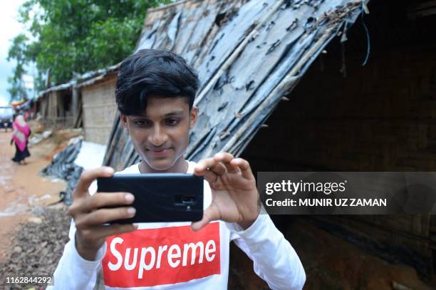 In this picture taken on July 23 Rohingya youth Mohammad Rafiq uses his mobile phone to take photos at the Kutupalong refugee camp. - Rafiq one of 30...