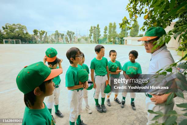 senior director is teaching baseball kids on field - nachwuchssportler auswahl sportveranstaltung stock-fotos und bilder