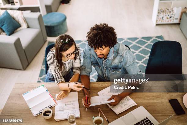 multi-etnisch echtpaar dat hun thuis budget plant - young couple at home stockfoto's en -beelden