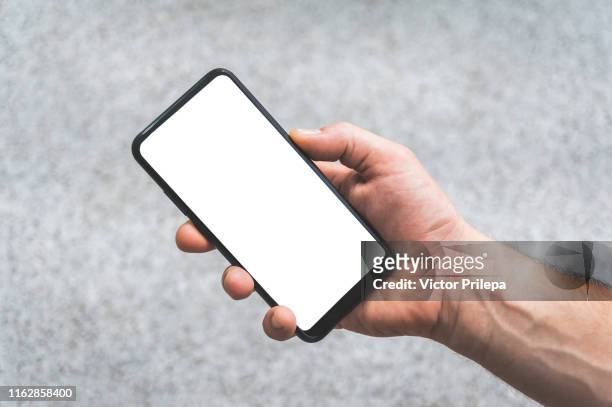 mock up of a smartphone in hand, on the background of concrete tiles. - cyborg fotografías e imágenes de stock