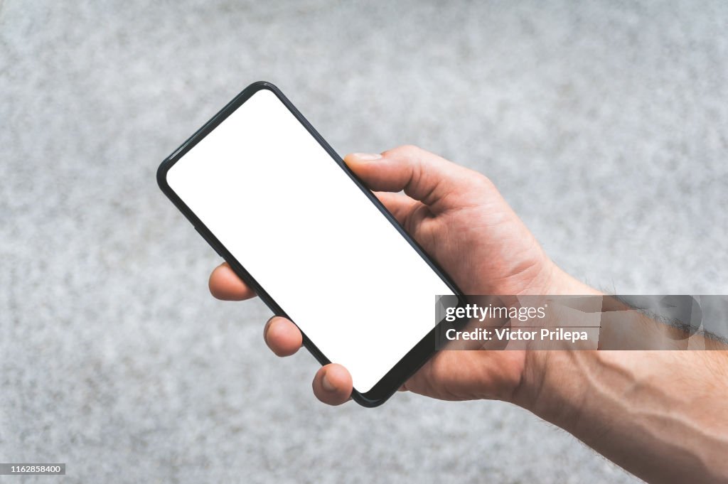 Mock up of a smartphone in hand, on the background of concrete tiles.