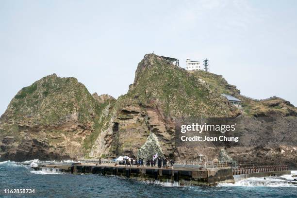Members of the South Korean Coat Guard greet at the tourists as they wave the Korean flag on the wharf on August 18, 2019 on Dokdo Islets, South...
