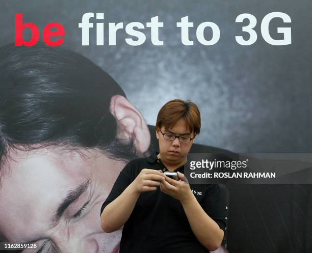 Man browses through a 3G mobile phone at the Singtel shop during its first day sale of its equipment, in Singapore 16 December 2004. Singapore...