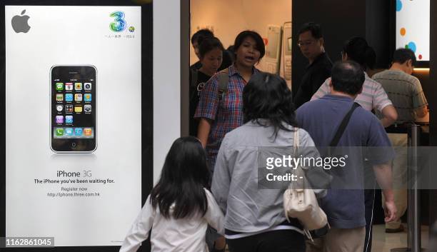 People walk into a shop selling the iPhone 3G in Hong Kong on July 13, 2008. In Hong Kong, more than 60,000 people have already ordered the iPhone...