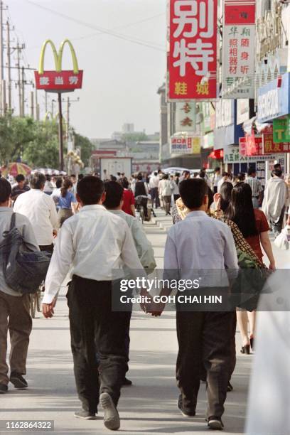 Two Chinese men walk hand-in-hand down a street in Beijing on May 21, 1997. - China has 5990 cases of HIV infection and 155 people suffering from...