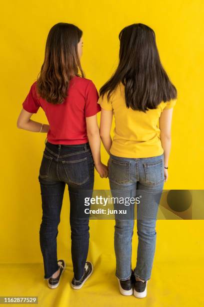 two beautiful girls in red and yellow embraced each other - buttocks gay stock pictures, royalty-free photos & images
