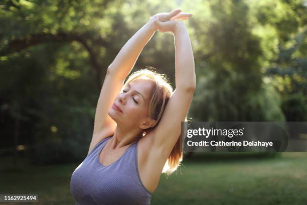 a woman praticing yoga in a park - adult gymnast feet stock-fotos und bilder