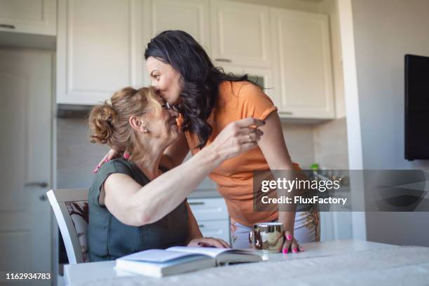 dochter zoenen haar moeder op het voorhoofd als een teken van liefde en zorg - mother daughter kitchen stockfoto's en -beelden