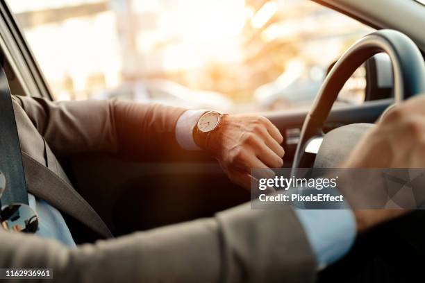 businessman is looking at watch in his car - wristwatch imagens e fotografias de stock