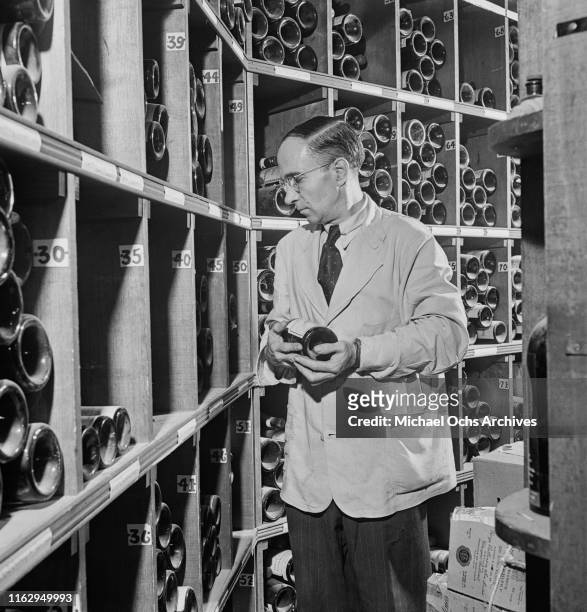 Waiter browsing bottles in the cellar of the 21 Club, restaurant and speakeasy on West 52nd Street in New York City, US, September 1945.