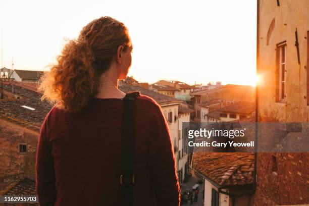woman looking out over rooftops in san miniato - san miniato stockfoto's en -beelden