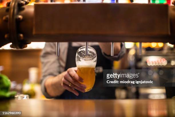 barista irriconoscibile che versa una birra in un pub - boccale foto e immagini stock