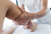 Masseur massaging the pregnant woman's legs in spa center.