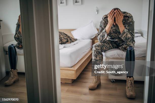 desperate disabled veteran us soldier sitting in bedroom alone - bed conflict stock pictures, royalty-free photos & images