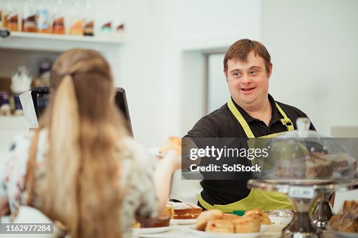 Eine Person mit Down-Syndrom serving in einem Cafe Eine Person mit Down-Syndrom serving in einem Cafe