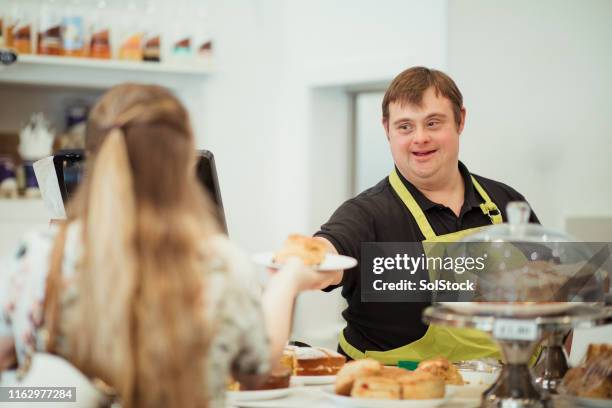 una persona con síndrome de down sirviendo en un café - down's syndrome fotografías e imágenes de stock