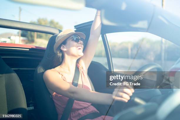 happy woman driving and celebrating with arm raised - car listening to music imagens e fotografias de stock