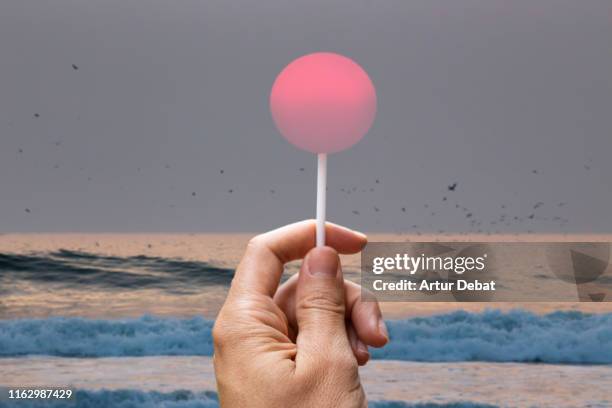 creative picture of sun like a lollipop in the beach. - ilusión óptica fotografías e imágenes de stock