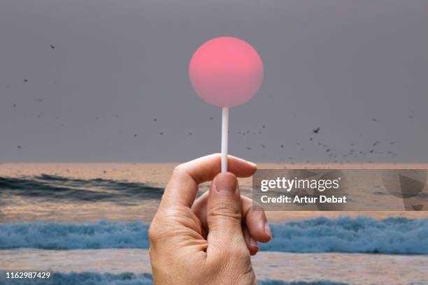 creative picture of sun like a lollipop in the beach. - gezichtsbedrog stockfoto's en -beelden