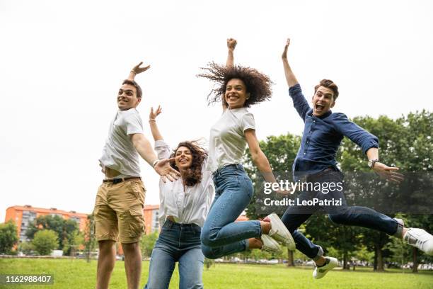 vrienden springen allemaal samen vieren succes - reünie sociaal stockfoto's en -beelden