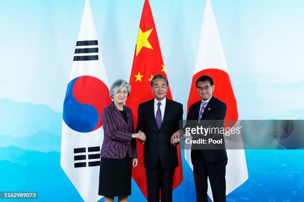 Chinese Foreign Minister Wang Yi , South Korean Foreign Minister Kang Kyung-wha and Japanese Foreign Minister Taro Kono shake hands ahead the ninth...