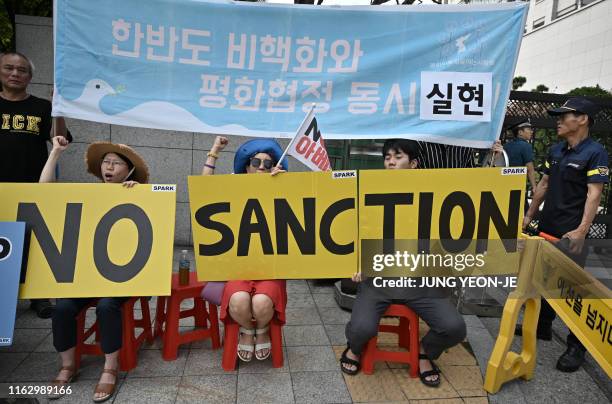 Anti-war activists hold placards as US Special Representative for North Korea Stephen Biegun arrives at the Foreign Ministry in Seoul on August 21,...