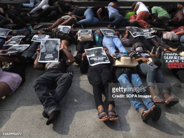 Protesters lie on the pavement with pictures of their relatives who are a victim of summary killings during the demonstration. Families of slain...