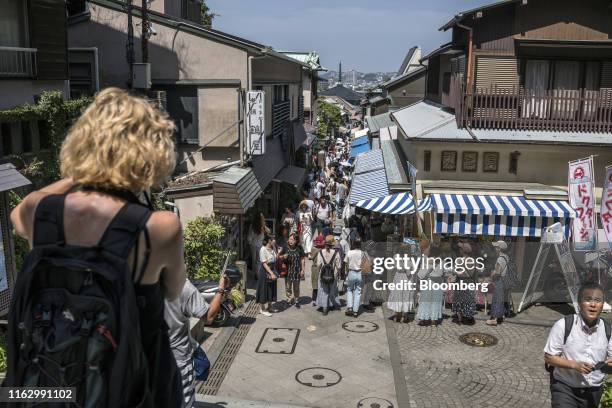 People walk along an alley lined with souvenir shops on Enoshima Island in Fujisawa, Kanagawa Prefecture, Japan, on Saturday, Aug. 17, 2019. The...